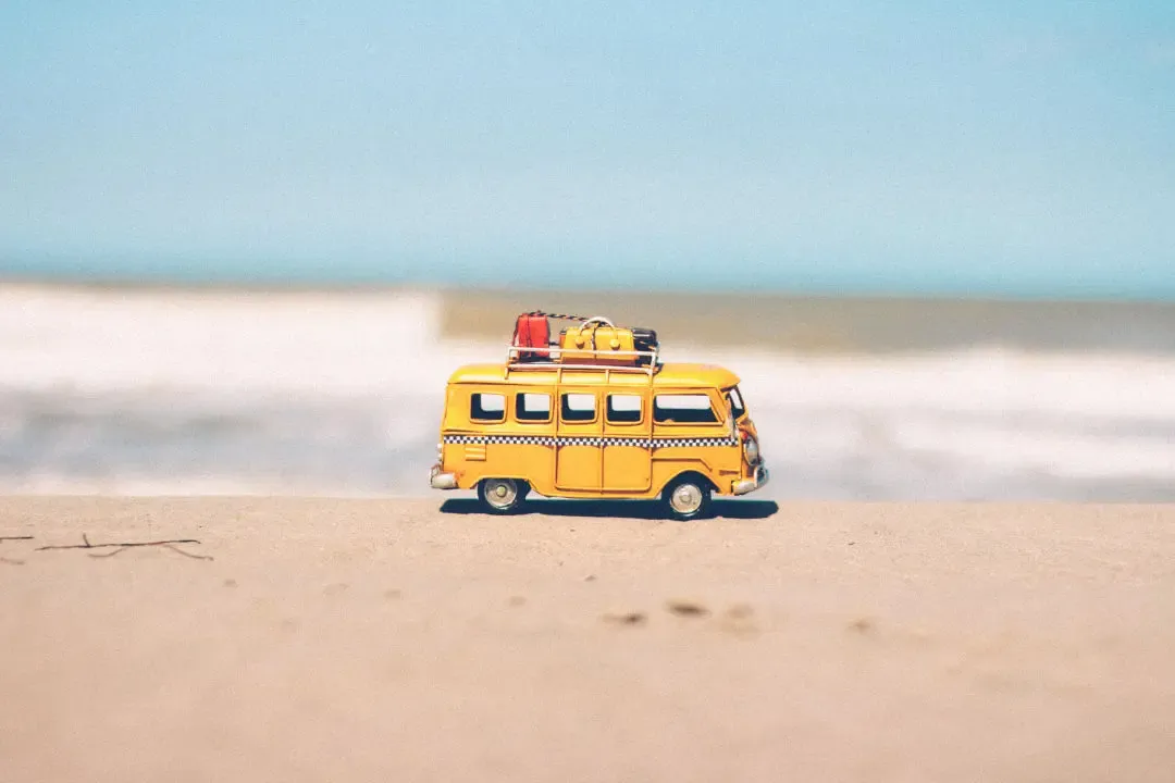 Ein Modell-Reisebus mit Gepäck auf dem Dach steht am Sandstrand